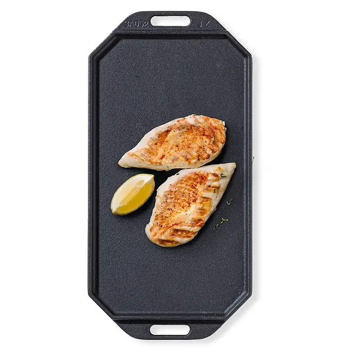 Cozze Grillpfanne - L x B: 30 x 15 cm, Höhe: 1 cm, Gusseisen - Gegrillte Hähnchenbrüste und eine Zitronenspalte auf einer dunkelgrauen Gusseisenplatte.