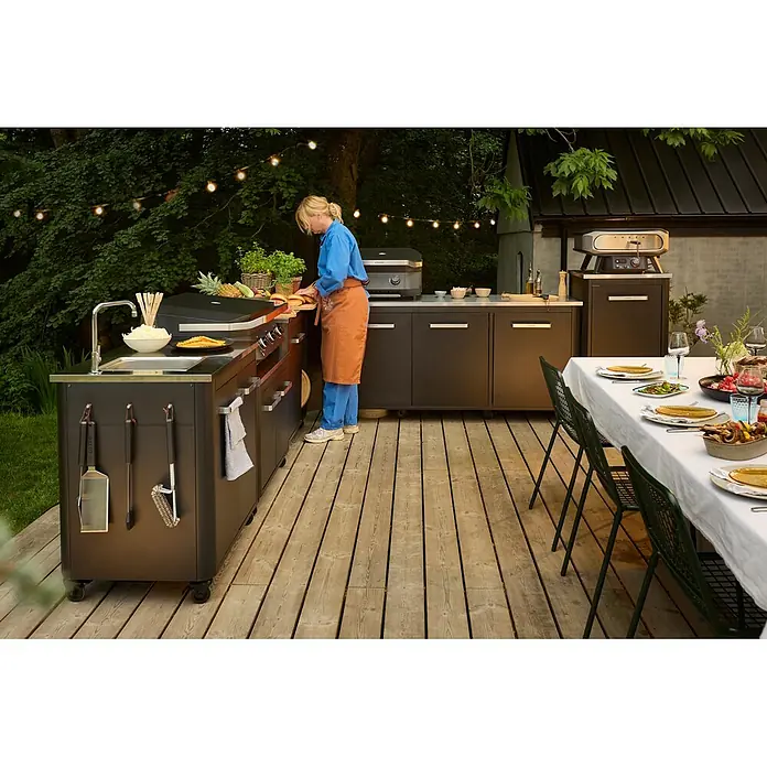 Cozze Outdoorküchen-Modul - Schwarz, B x T x H: 180 x 60 x 90 cm - Eine dunkelgraue, modulare Außenküche mit Grill, Spüle, Schränken und einem Pizzaofen, zum Kochen im Freien genutzt.