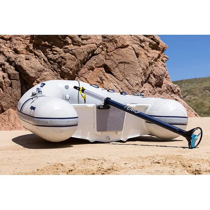 Temo Elektro-Außenbordmotor 450 - Leistung: 450 W, Pinnensteuerung - Weißes Schlauchboot mit blau akzentuiertem Elektromotor und hellblauem Propeller, am Sandstrand.