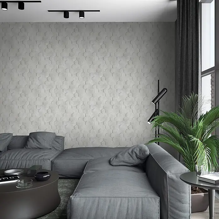 Marburg Loft Superior Vliestapete Grafik - Greige, Grafisch, 10,05 x 0,53 m - Helle graue sechseckige Wandpaneele bilden eine strukturierte Akzentwand in einem modernen Wohnzimmer mit großem Sofa.