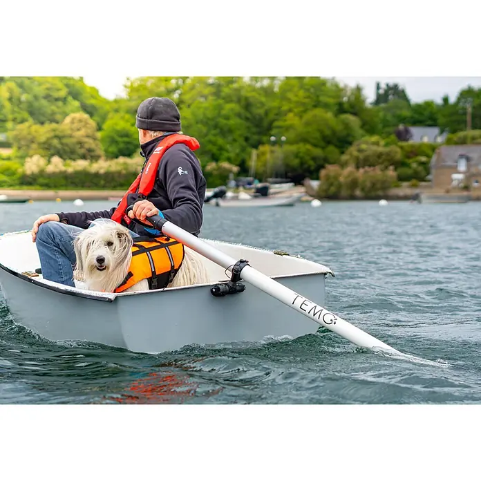 Temo Elektro-Außenbordmotor 450 Nacre-Edition - 450 W, Pinnensteuerung - Weißes TEMO-Ruder, von Person in kleinem Boot mit Hund in Rettungsweste genutzt.