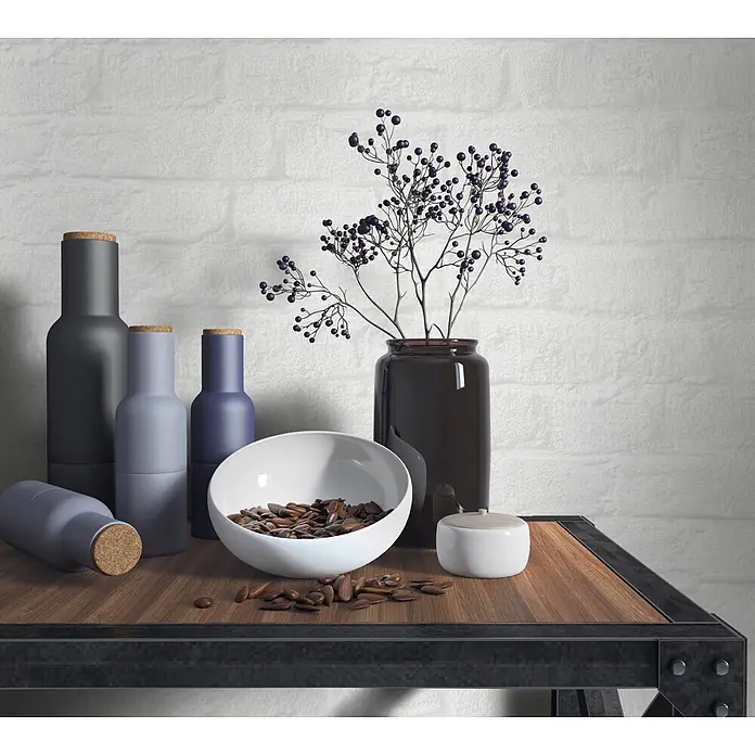 Marburg Loft Superior Vliestapete Steinoptik - Weiß, Steinoptik, 10,05 x 0,53 m - Auswahl matter Flaschen, weißer Schale Nüssen und dunkler Vase mit Beeren auf Holzregal.