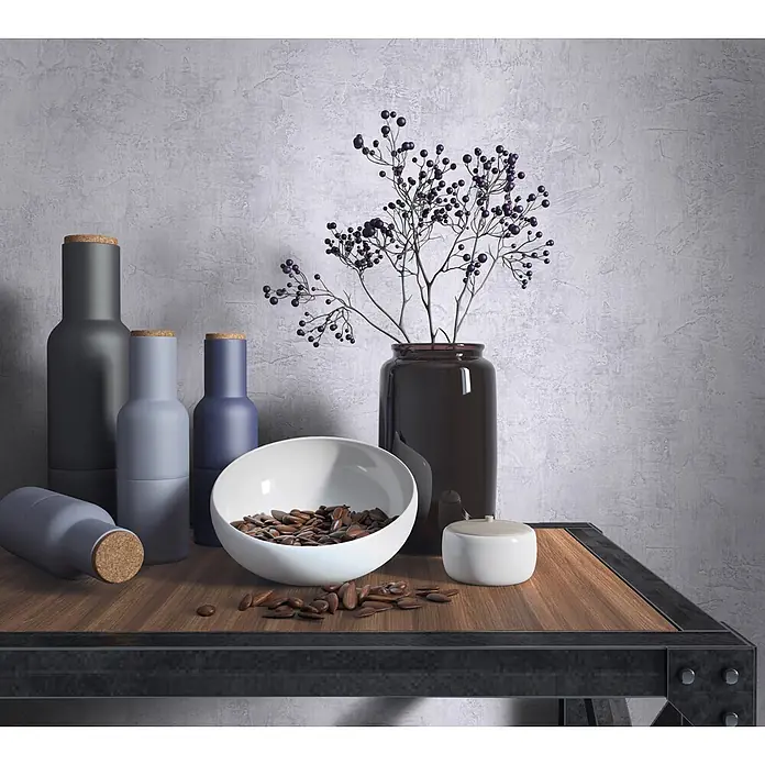 Marburg Loft Superior Vliestapete Struktur I - Steingrau, Sonstiges, 10,05 x 0,53 m - Eine Sammlung matter Flaschen, eine weiße Schale mit Samen und eine Vase mit Beerenästen auf einem Holzregal, als stilvolle Heimdekoration.