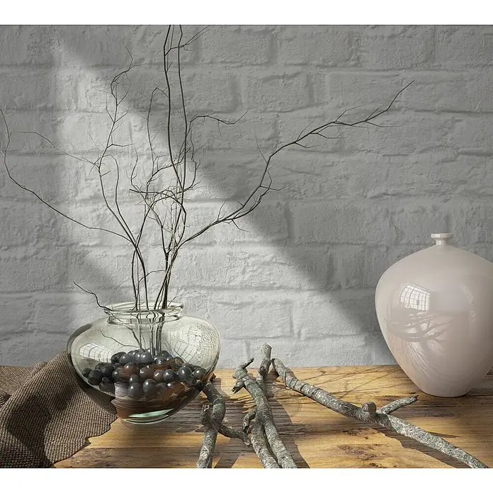 Marburg Loft Superior Vliestapete Steinoptik - Greige, Steinoptik, 10,05 x 0,53 m - Tischdeko: Glasvase mit trockenen Zweigen und dunklen Perlen, beige Keramikvase und Naturzweige auf Holz.