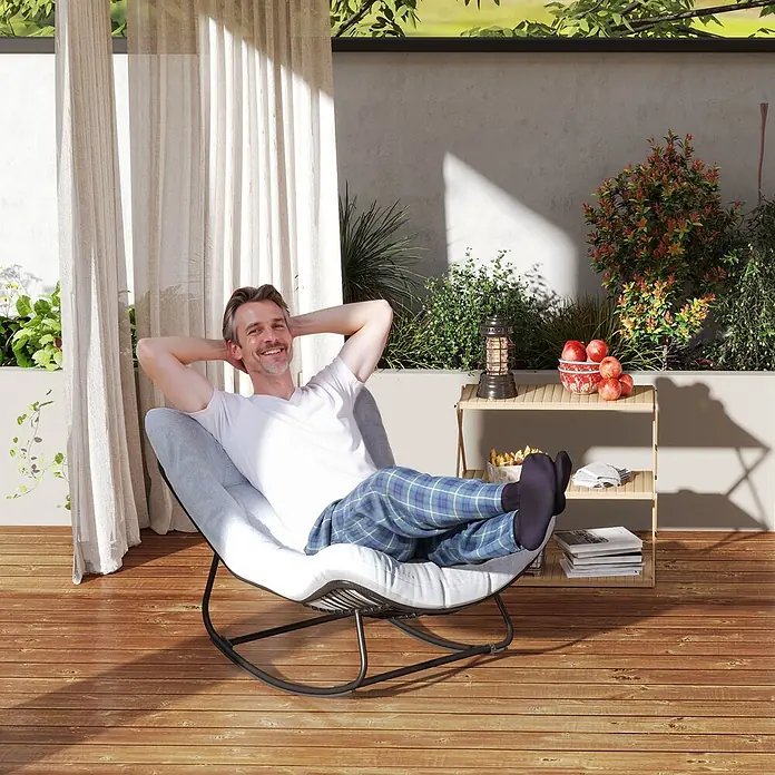 Outsunny Garten-Schaukelstuhl mit abnehmbarem Bezug, 120 kg Traglast - 1 Stk., PE-Rattan, Schwarz, Hellgrau, B x T x H: 98 x 111 x 74 cm - Mann entspannt sich in einem hellgrauen Schaukelstuhl mit dunklem Metallgestell auf einem Holzbalkon im Freien.