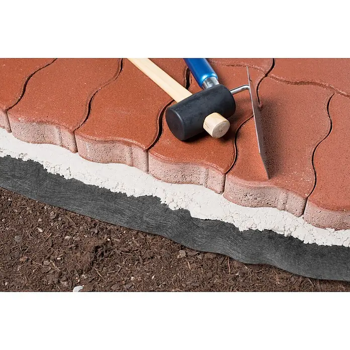 Windhager Trenn- & Filtervlies - L x B: 7 x 0,9 m, Grau - Rote Verbundpflastersteine mit Sand und Geotextil auf Erde, dazu Gummihammer und Kelle, zeigen Pflasterverlegung.