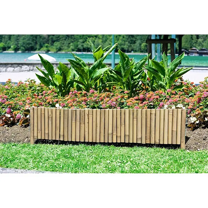 Windhager Beeteinfassung Typ 3 - Bambus, 100 x 35 cm - Segment einer natürlichen Bambus-Gartenbegrenzung, das ein Blumenbeet mit rosa und orangen Blumen vom grünen Gras trennt.