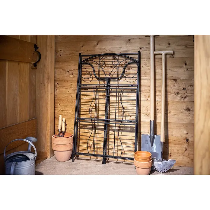 Windhager Metallregal 3-stufig - Pulverbeschichtet, Gerade - Faltbares Gartenspalier aus schwarzem Metall an Holzwand, umgeben von Gartengeräten und Terrakottatöpfen.