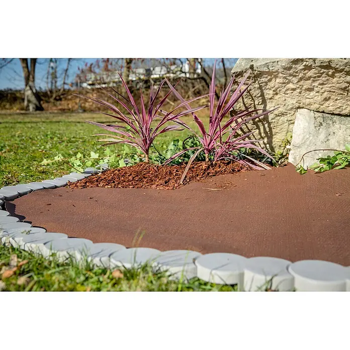 Windhager Unkrautvlies Premium - Vlies, 10 x 0,9 m - Graue, halbkreisförmige Beetsteine begrenzen ein bepflanztes Beet mit braunem Mulch und Unkrautvlies.
