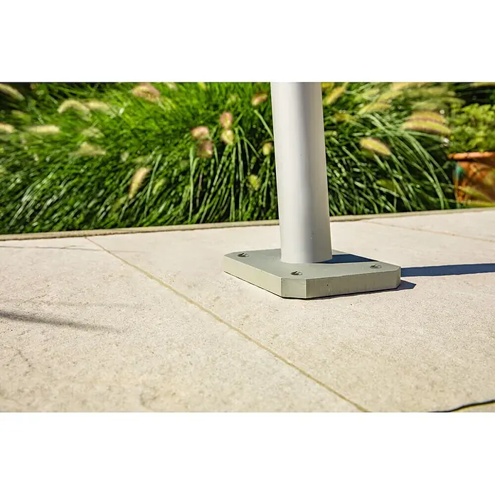 Windhager Terrassenhalterung Premium - Geeignet für: Sonnenschutzbefestigungen - Hellgraue Metallpfostenbasis auf Pflastersteinen im Freien, umgeben von grünem Laub.