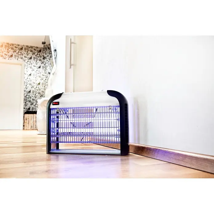 Windhager UV-Mückenlampe Comfortable+ - 16 W, Wirkungsbereich: 40 m² - Weiße und schwarze Insektenfalle mit violett leuchtenden Lichtern, auf einem Holzboden in einem Raum.