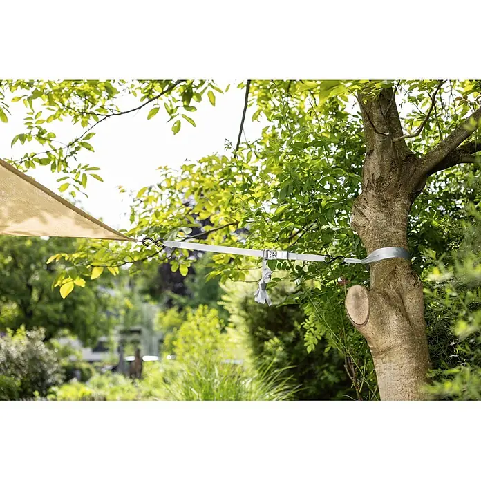 Windhager Spanngurt Sun Sail inklusive Ratsche - Geeignet für: Sonnensegel - Weißes Spanngurtsystem befestigt ein beiges Sonnensegel an einem Baum im Garten.