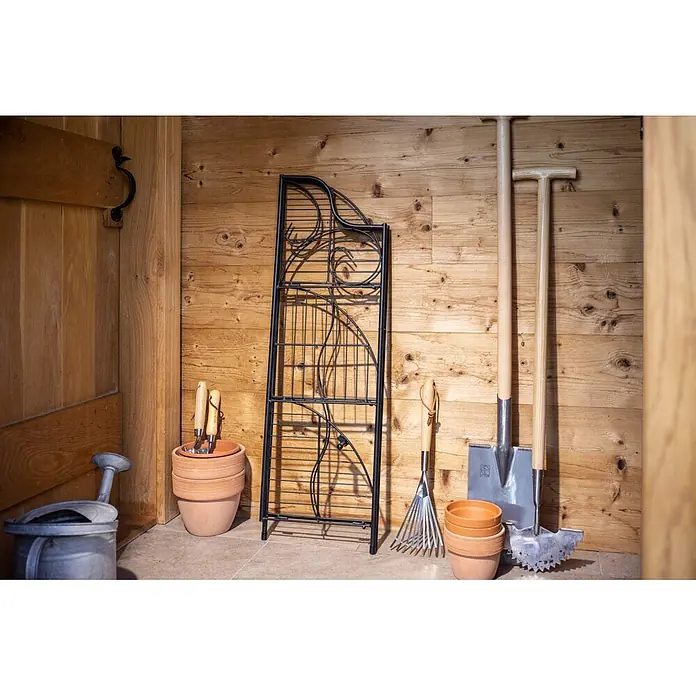 Windhager Metallregal 3-stufig - Pulverbeschichtet, Eckig - Auswahl an Gartengeräten: Terrakottatöpfe, Handwerkzeuge, Spaten, Gießkanne, Rechen und ein schwarzes Metallspalier, an einer Holzwand.