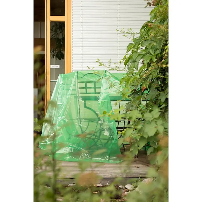 Windhager Abdeckfolie Outdoor - L x B: 10 x 2 m - Gartenmöbel, bestehend aus Tisch und Stühlen, auf einer Holzterrasse mit einer durchscheinenden grünen Plastikabdeckung geschützt.