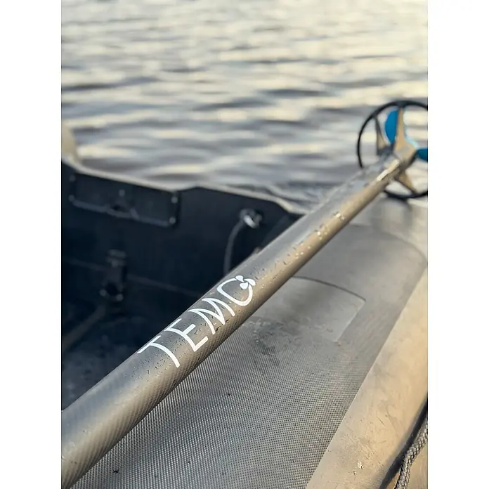 Temo Elektro-Außenbordmotor 450 Carbon - 450 W, Pinnensteuerung - TEMO Elektromotorschaft mit blauem Propeller auf einem Schlauchboot. Wasser im Hintergrund.