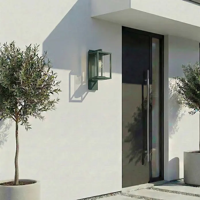 Lucande Außenwandleuchte Ferda - grün, grün, IP44 - Moderne dunkelgrüne Außenwandleuchte an weißer Hausfassade neben dunkler Tür.