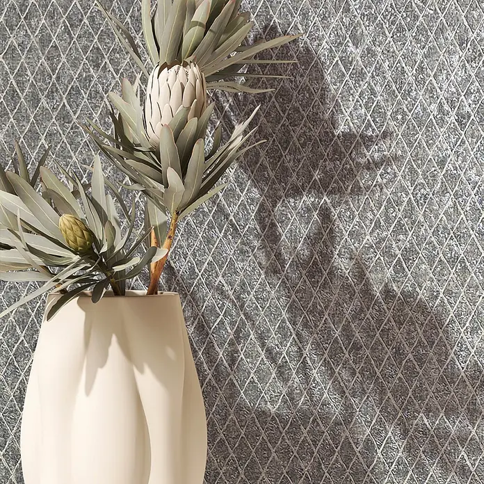 Marburg Ritus Vliestapete Grafik II - Grau-Weiß, Grafisch, 10,05 x 0,53 m - Cremefarbene Vase mit Protea-Blumen und Blättern vor einer strukturierten Wand mit Rautenmuster, die Schatten wirft.