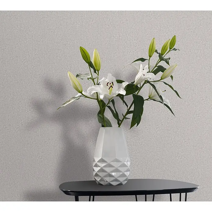 Marburg Ritus Vliestapete Putzoptik I - Grau, Sonstiges, 10,05 x 0,53 m - Weiße Vase mit geometrischer Textur, gefüllt mit weißen Lilien, auf einem dunkelgrauen Tisch.