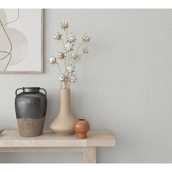 Marburg Ritus Vliestapete Putzoptik I - Weiß-Grau, Sonstiges, 10,05 x 0,53 m - Heller Holztisch mit gerippter Platte, dekoriert mit Vasen und gerahmter Kunst in minimalistischem Interieur.