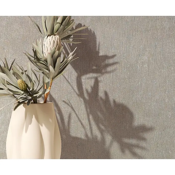 Marburg Ritus Vliestapete Uni I - Beige, Uni, 10,05 x 0,53 m - Skulpturale cremefarbene Vase mit zwei Proteablüten, einer geöffneten und einer Knospe, vor einer strukturierten Wand mit Schatten.