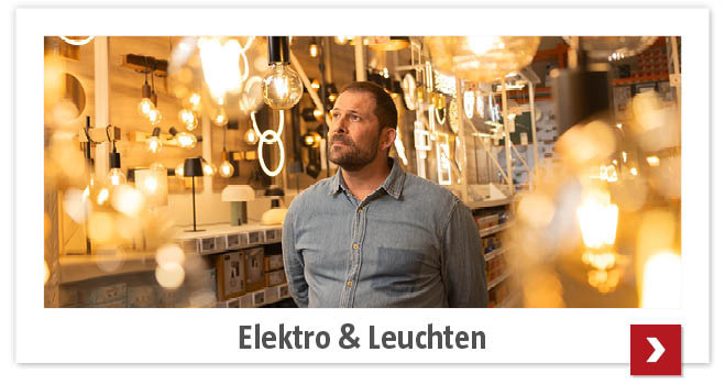 Mann geht in der Leuchten-Abteilung mit vielen, eingeschalteten Lampen