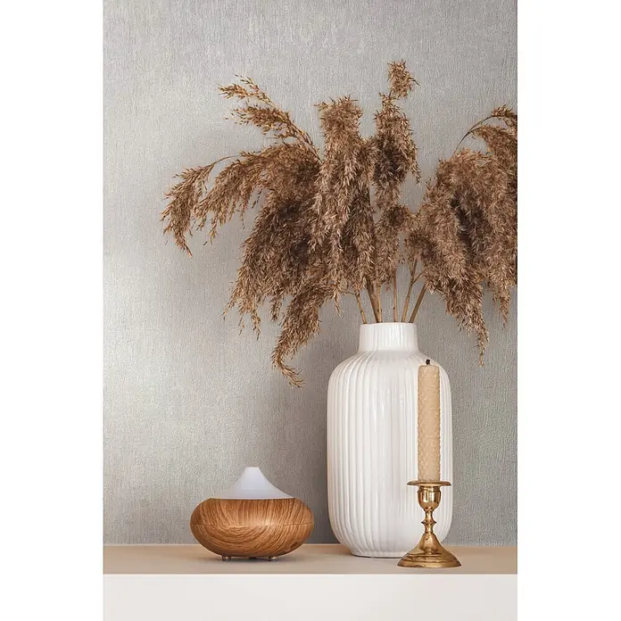 Marburg Ritus Vliestapete Uni I - Weiß-Grau, Uni, 10,05 x 0,53 m - Aroma-Diffusor in Holzoptik, weiße Vase mit Pampasgras und Messingkerzenhalter mit Kerze auf einem Regal.