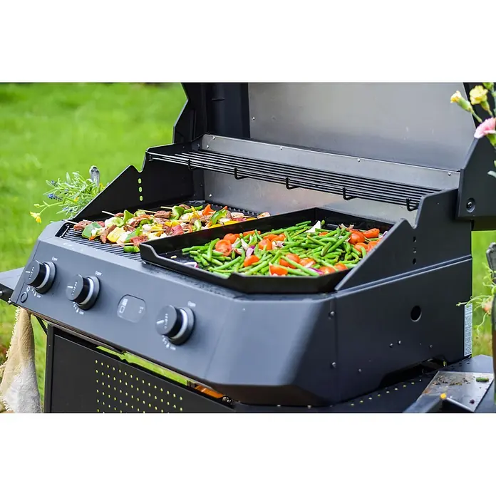 Cozze Gasgrill G 800 Combo - Grillfläche (B x T): 81,5 x 42 cm, 9,5 kW, Anzahl Brenner: 3 Stk. - Schwarzer Gasgrill, auf dem bunte Fleisch- und Gemüsespieße sowie eine Pfanne mit grünen Bohnen, Tomaten und roten Zwiebeln zubereitet werden.