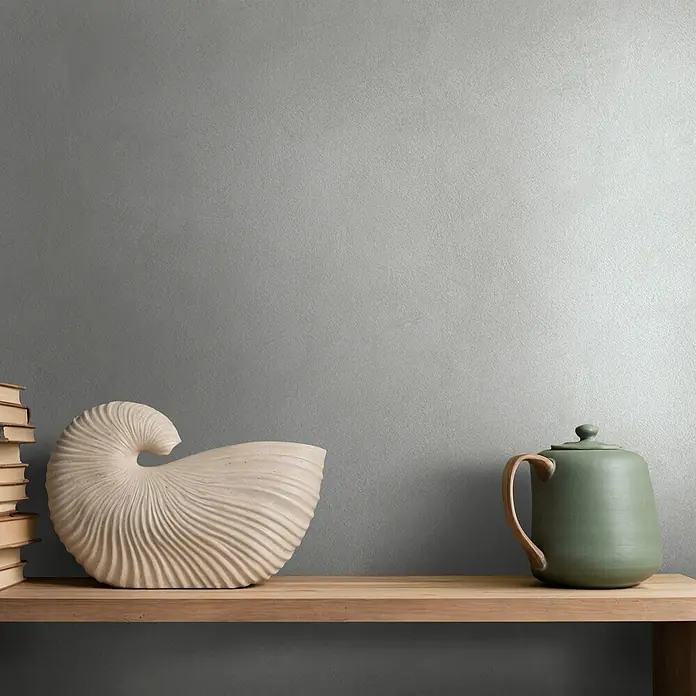 Marburg Whisper Vliestapete Putzoptik - Grau, Sonstiges, 10,05 x 0,53 m - Dekorative Nautilus-Skulptur und salbeigrüne Keramik-Teekanne mit Holzgriff auf einem Holzregal.