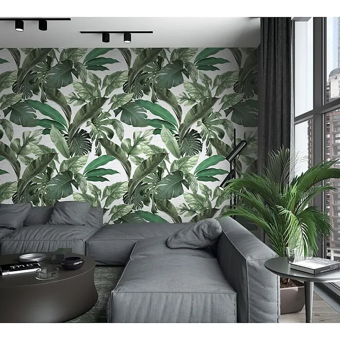 Marburg Loft Superior Fototapete Urban Jungle - B x H: 159 mm x 270 cm, Vlies, Grün-Weiß - Ein modernes Wohnzimmer mit einem großen grauen modularen Sofa und einer weißen Wand mit tropischer Blatttapete.