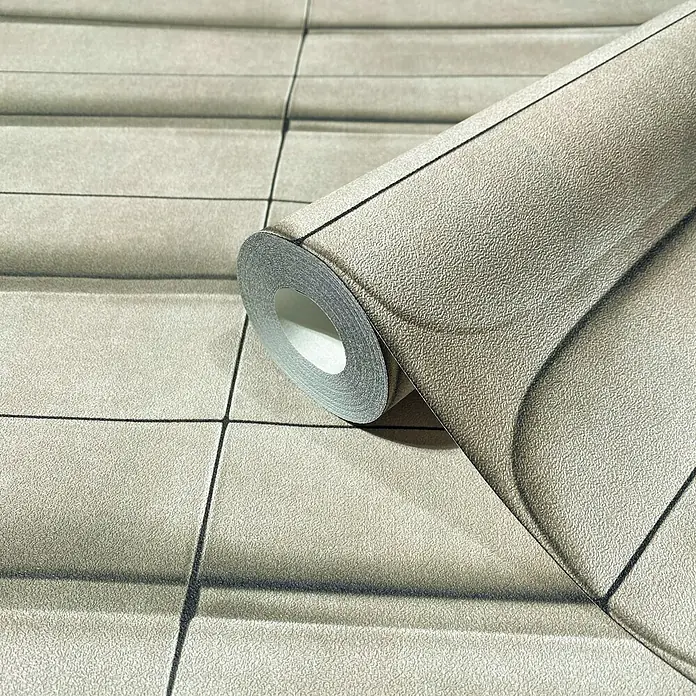 Marburg Shades Iconic Vliestapete Grafik III - Beige, Grafisch, 10,05 x 0,53 m - Strukturierte, graubeige Tapetenrolle mit erhabenem geometrischem Fliesenmuster, teilweise abgerollt, um die Rückseite zu zeigen.