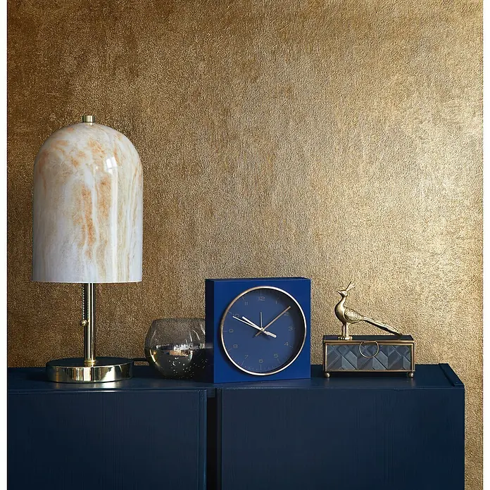 Marburg City Glow Vliestapete Struktur - Gold, Sonstiges, 10,05 x 0,53 m - Dunkelblauer Schrank mit Marmorlampe, blauer Uhr und goldener Vogeldekoration vor goldener Strukturwand.