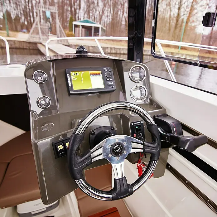 PEGAZUS GFK-Boot 560 Top Fisher 115 - Motorleistung 84.6 kW/115 PS, Geeignet für: Max. 6 Personen, CE-Klasse C - Nahaufnahme des Steuerstands eines Bootes, der ein Steuerrad, einen Lowrance-Bildschirm, Messgeräte und Bedienelemente zeigt.