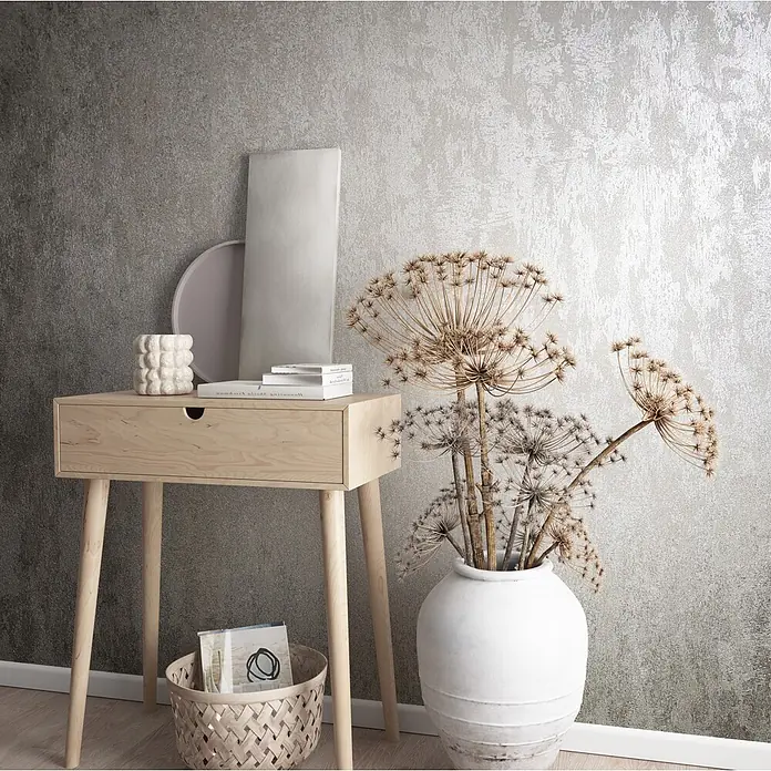 Marburg City Glow Vliestapete Struktur - Grau-Pearl, Sonstiges, 10,05 x 0,53 m - Heller Konsolentisch aus Holz mit Schublade, dekoriert mit Trockenblumen und Dekoartikeln vor einer strukturierten Wand.