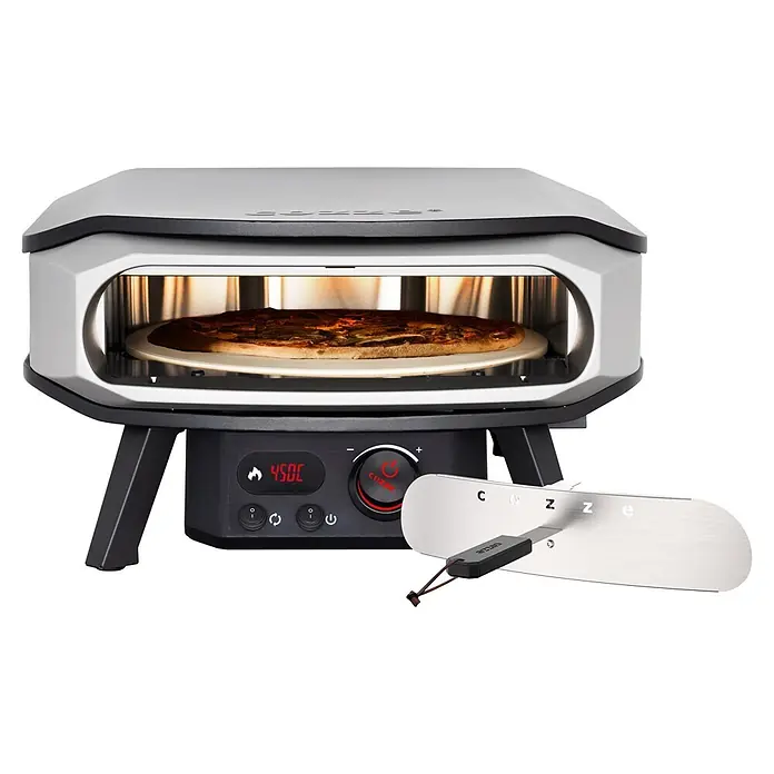 Cozze Pizzaofen Elektro Premium 17" - Grillfläche (B x T): 42,5 x 42,5 cm, 2,2 kW - Ein silber-schwarzer Pizzaofen mit backender Pizza und einem silbernen Pizzaschieber daneben.