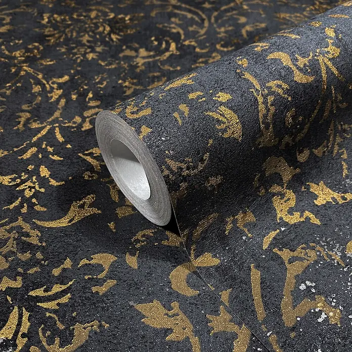 Marburg City Glow Vliestapete Ornamental - Schwarz-Gold, Ornament, 10,05 x 0,53 m - Rolle strukturierter schwarzer Tapete mit gold-silbernem Ornamentmuster, teilweise abgerollt.