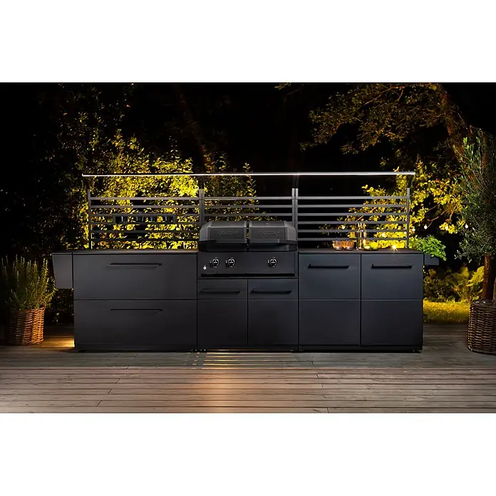 Cozze Elements Arbeitsplatte -  - Matte schwarze Außenküche mit integriertem Grill auf Holzdeck, nachts beleuchtet mit warmem Umgebungslicht.