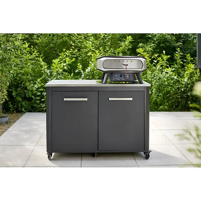 Cozze Pizzaofen Elektro Premium 17" - Grillfläche (B x T): 42,5 x 42,5 cm, 2,2 kW - Outdoor-Pizzaofen aus Edelstahl auf einem dunkelgrauen mobilen Outdoor-Küchenschrank mit Edelstahlplatte auf einer Terrasse.