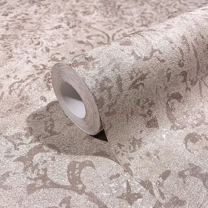 Marburg City Glow Vliestapete Ornamental - Braun, Ornament, 10,05 x 0,53 m - Hellbraune, strukturierte Tapetenrolle mit Distressed-Damaschkmuster, teilweise abgerollt.