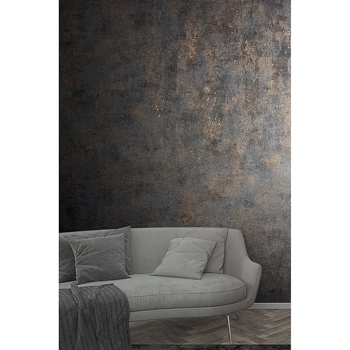 Marburg City Glow Vliestapete Uni - Schwarz-Gold, Uni, 10,05 x 0,53 m - Helles graues Sofa mit dunklen Kissen und einer Decke vor einer dunklen, strukturierten Wand mit Goldakzenten.