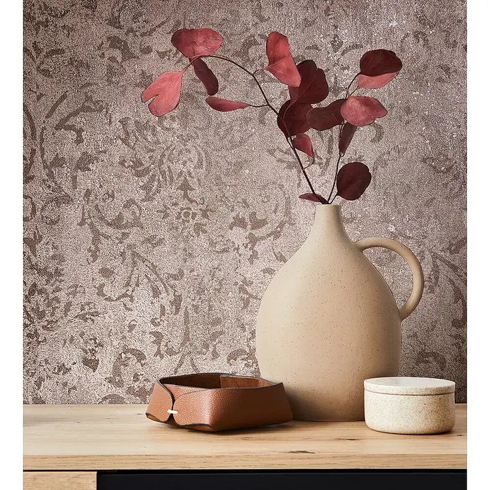Marburg City Glow Vliestapete Ornamental - Braun, Ornament, 10,05 x 0,53 m - Stillleben mit beiger gesprenkelter Keramikvase, roten Trockenblättern, braunem Ledertablett und kleiner Dose mit Deckel auf Holzoberfläche.