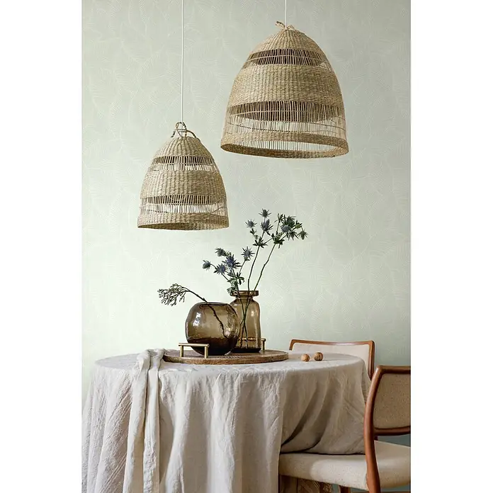 Marburg Novamur Plus Fresh UP Vliestapete Flora VII - Grün, Floral, 10,05 x 0,53 m - Zwei glockenförmige geflochtene Pendelleuchten hängen über einem Tisch vor einer gemusterten Tapete.