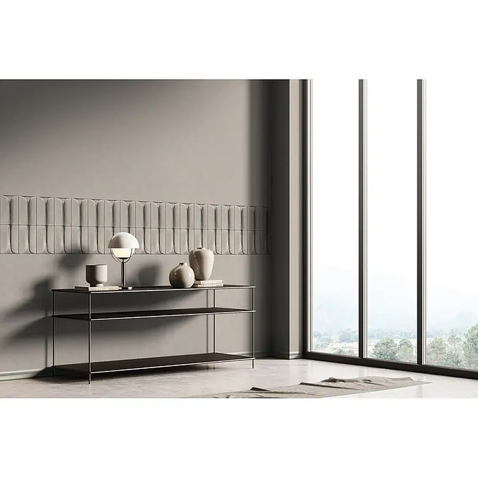 Marburg Shades Iconic Vliestapete Grafik III - Beige-Grau, Grafisch, 10,05 x 0,53 m - Ein schlanker Konsolentisch mit schwarzen Ablagen und silbernem Rahmen, dekoriert mit einer Lampe, Vasen und Büchern, in einem modernen Raum mit Zierwandpaneelen.