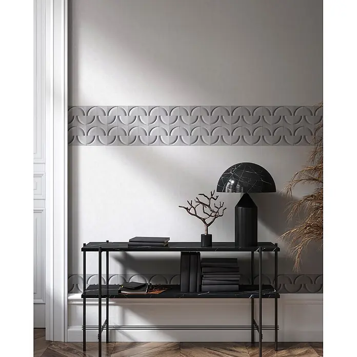 Marburg Shades Iconic Tapetenborte Grafik - Grau, Grafisch, 5 x 0,18 m, Vlies - Schwarzer Konsolentisch aus Metall mit zwei schwarzen Marmorplatten, dekoriert mit Büchern, einer Lampe und einer Zierästchen.