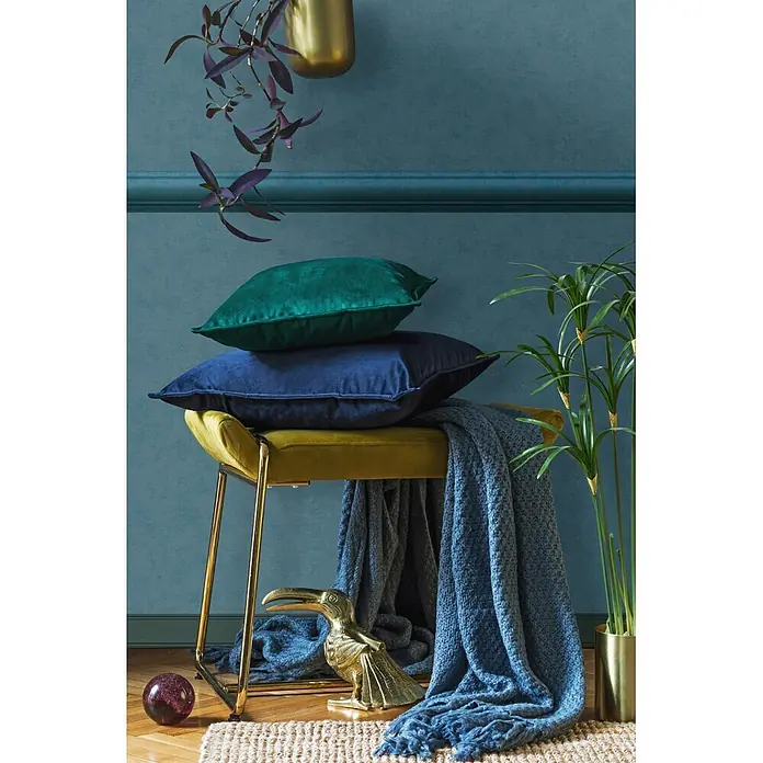 Marburg Shades Iconic Tapetenborte Streifen - Blau, Architektur, 5 x 0,09 m, Vlies - Eine gelbe Samtbank mit Goldbeinen, bedeckt mit grünen und blauen Samtkissen und einer blauen Strickdecke, in einem teal-farbenen Raum inszeniert.