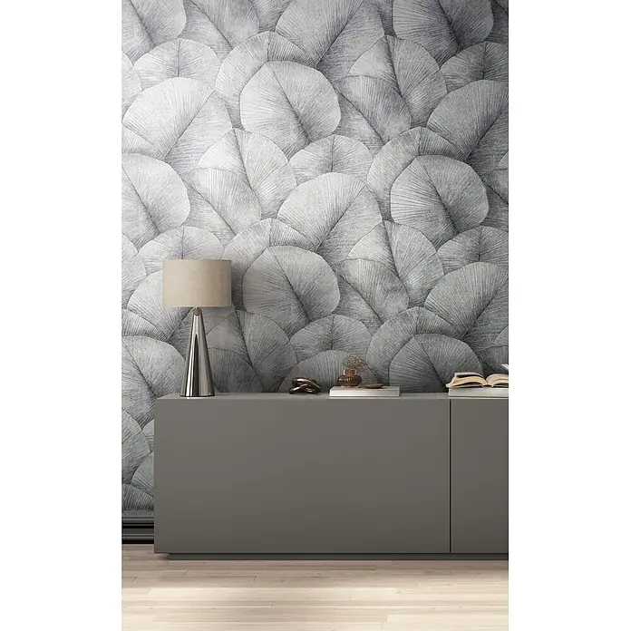 Marburg Kumano Vliestapete Floral - Grau, Floral, 10,05 x 0,53 m - Dunkelgraues Sideboard in minimalistischem Design, mit Lampe und Dekoartikeln vor gemusterter Tapete.