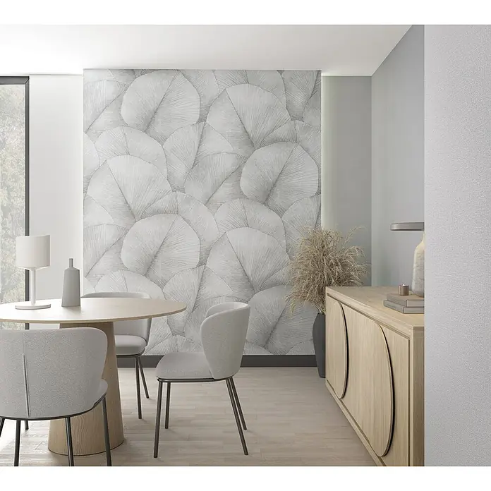 Marburg Kumano Fototapete Floral - B x H: 212 x 270 cm, Vlies, Grau - Ein moderner Essbereich mit einem runden Holztisch, hellgrauen Stühlen und einer strukturierten Akzentwand. Ein Holzsideboard ergänzt den Raum.