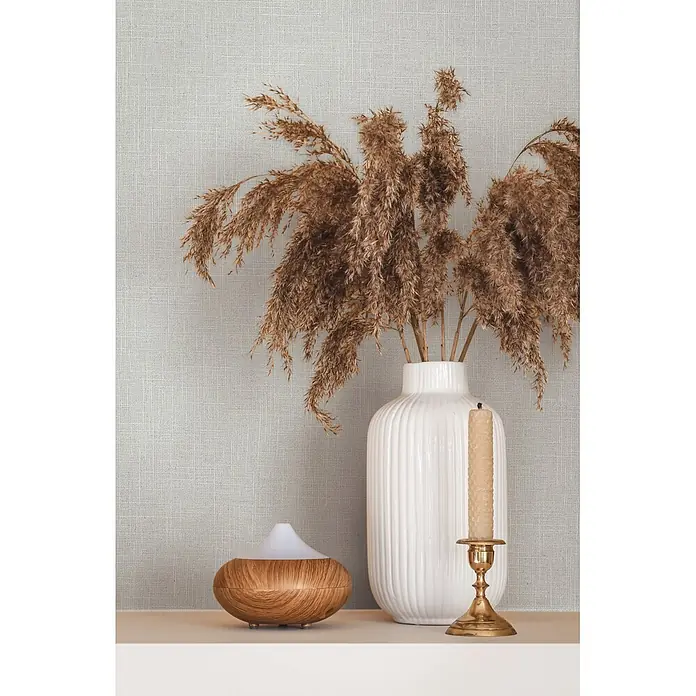 Marburg Boho Vliestapete Uni I - Beige-Grau, Uni, 10,05 x 0,53 m - Wohnaccessoires: getrocknetes Pampasgras in weißer gerippter Vase, Holz-Diffusor und Bienenwachskerze in Messinghalter.