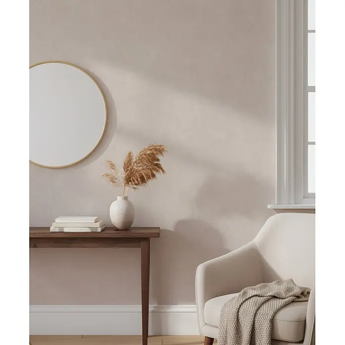 Marburg Whisper Vliestapete Putzoptik I - Beige-Braun, Sonstiges, 10,05 x 0,53 m - Gemütlicher Wohnbereich mit rundem Spiegel, Konsolentisch mit Büchern und Pampasgras sowie cremefarbenem Sessel mit Decke.
