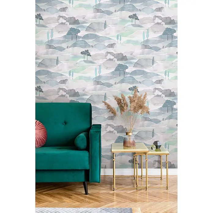 Marburg Boho Vliestapete Landscape - Weiß-Grün-Blau, Sonstiges, 10,05 x 0,53 m - Luxuriöses grünes Samtsofa mit einem pinken Kissen neben zwei eleganten goldfarbenen Beistelltischen mit Dekoration.