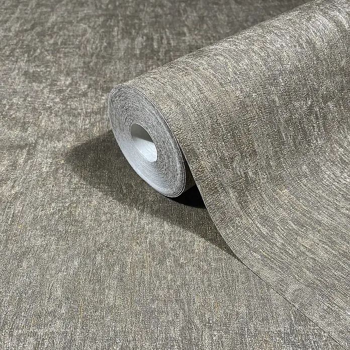Marburg Ritus Vliestapete Uni I - Grau-Braun, Uni, 10,05 x 0,53 m - Strukturierte grau-braune Tapetenrolle mit goldenen Metallpartikeln, teilweise abgerollt, um ihr gewebtes Muster zu zeigen.